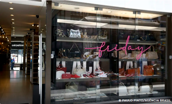 Vitrine de loja com bolsas e acessórios expostos e letreiro “Friday” em neon rosa.