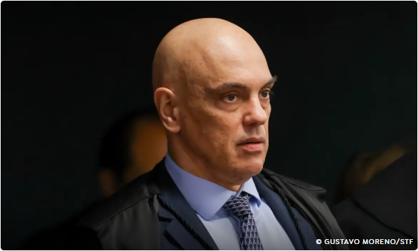 Alexandre de Moraes, ministro do STF, observa à frente durante sessão, usando toga e gravata.
