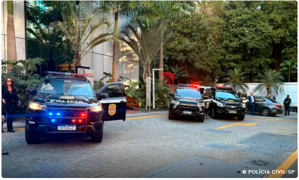 Viaturas da Polícia Civil de São Paulo estacionadas em frente a um prédio durante operação, com agentes no local.