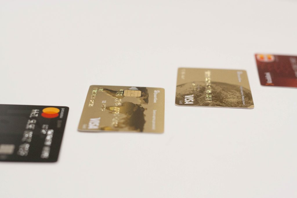 Cartões de crédito de diferentes bandeiras dispostos sobre superfície clara.